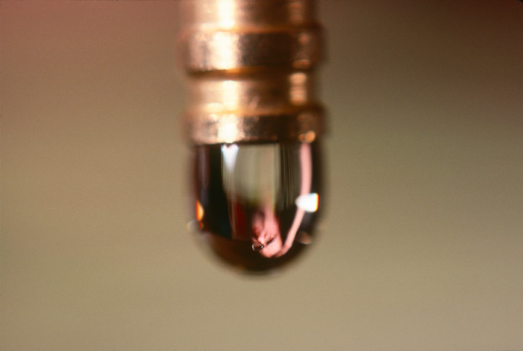 Detail, close up of a drip of water, man reflected in the drip